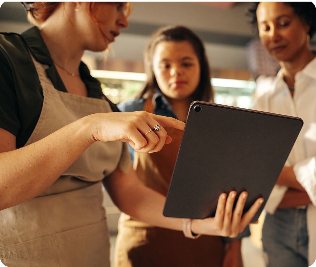 Store employees using a tablet to assist a customer at the checkout counter