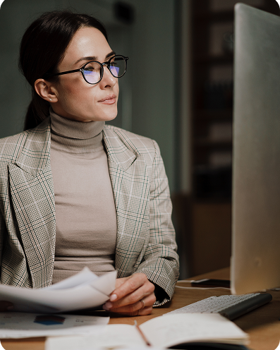 Woman looking at a screen with papers in front of her