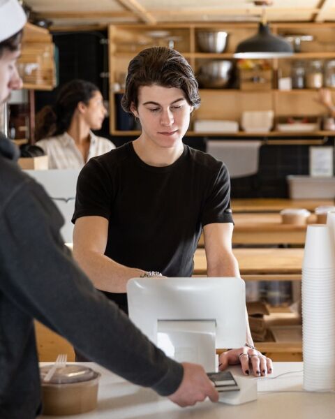 Restaurant employee working at a point-of-sale terminal behind the counter
