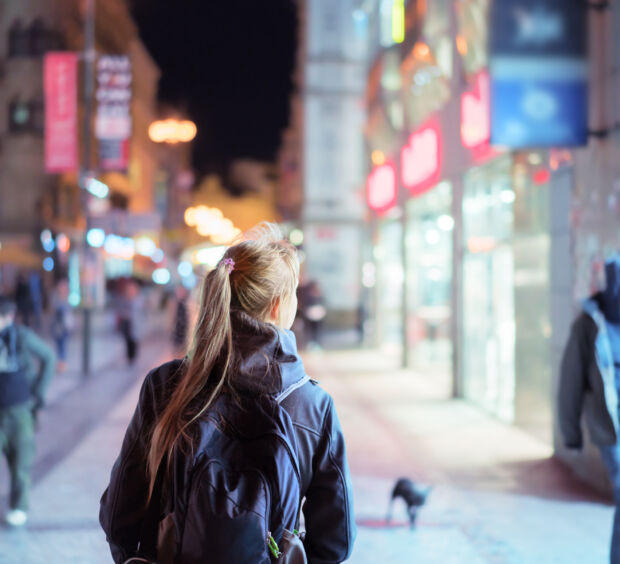 Back view of girl walking on city street at night, Prague
