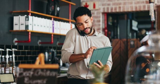 Phone call, conversation and man on tablet in restaurant for online orders, inventory delivery and schedule. Manager, hospitality and person on tech for communication, stock supplier and logistics.